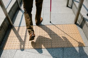 A photo of a person's legs. walking over a tactile sidewalk grate using a white cane. Featured Image for Blind and Low Vision Homebuyers